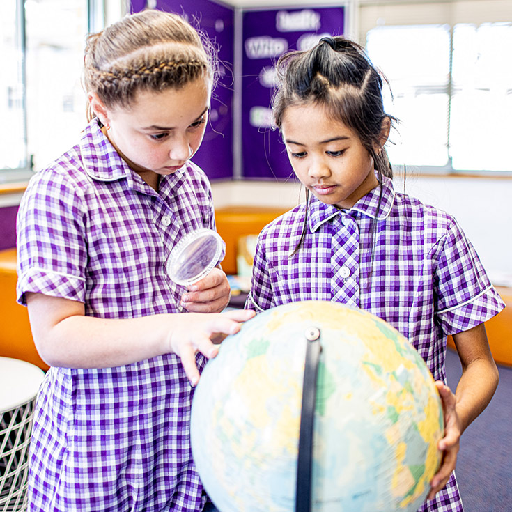 Girls inspecting globe at Holy Cross Catholic Primary Glenwood