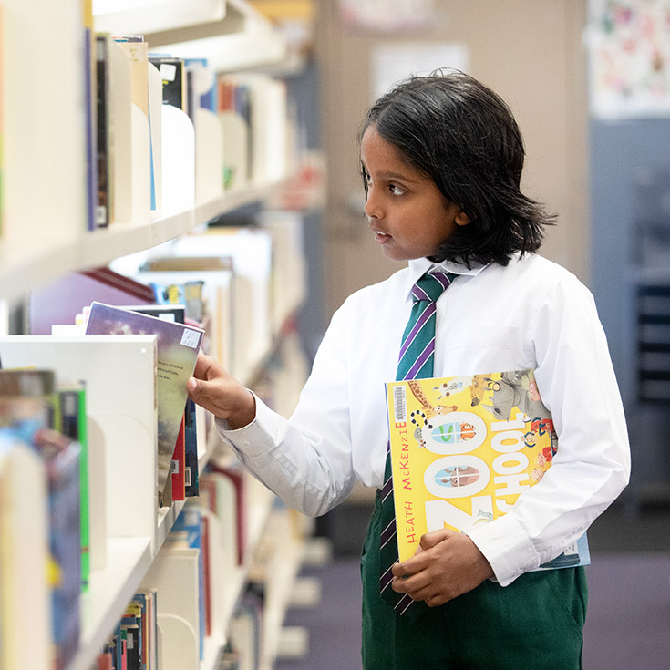 Holy Cross Catholic Primary Glenwood girl selecting books of library shelves