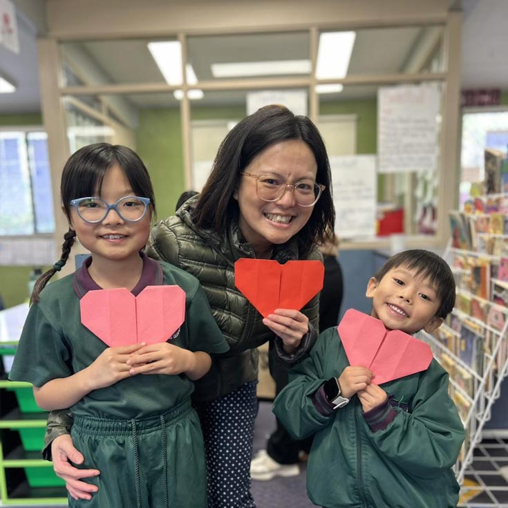 Holy Cross Glenwood mother and her two children. They are holding heart shaped crafts